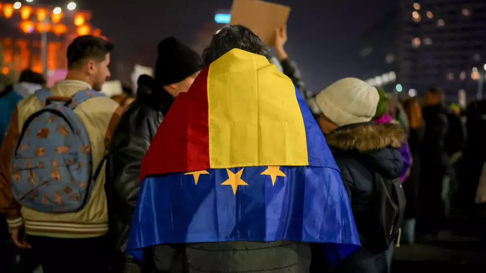 Чоловік із прапорами Румунії та ЄС на плечах на протесті проти Келіна Джорджеску © Vadim Ghirda / AP