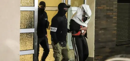 Поліцейські виводять людину з будинку в Хагені, на заході Німеччини, у середу в рамках операції проти «Ндрангети». Фото: Алекс Талаш/AFP/Getty Images